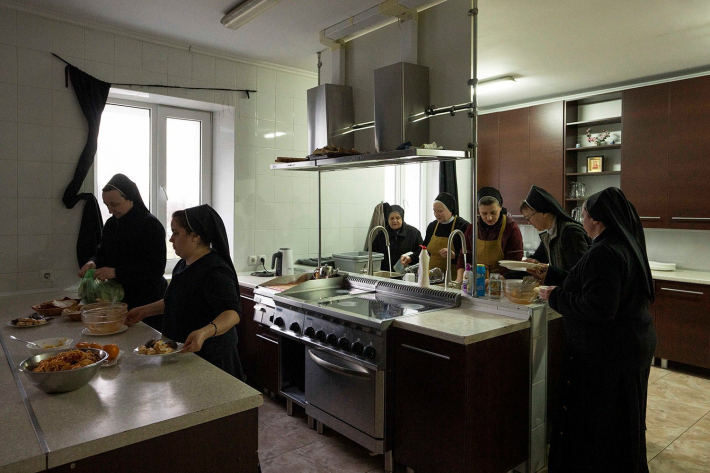 Монахині та вимушені переселенці миють посуд після обіду
